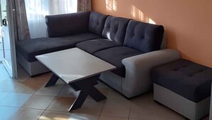 A modern living room with a sectional sofa, a coffee table, and a large window with curtains.