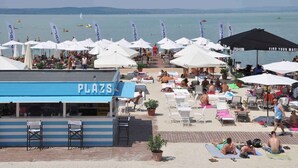 A beachside area with multiple umbrellas, lounge chairs, and a 'PLAZA' sign.
