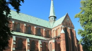 A large brick building with a prominent tower and arched windows.