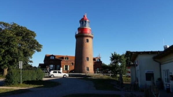 A lighthouse with a red top, surrounded by trees and a few buildings. - Premium apartment by the sea, sea view, large balcony (Börgerende-Rethwisch)