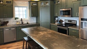 A kitchen with green cabinets, stainless steel appliances, and pendant lighting. - Beautiful lake house with pontoon INCLUDED! (Vergas)