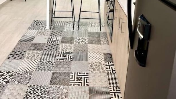 Une cuisine moderne dotée d’un îlot central, de deux suspensions et d’un tapis à motifs.