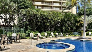 Un área de piscina con sillones de descanso y un deck cubierto de baldosas de piedra.