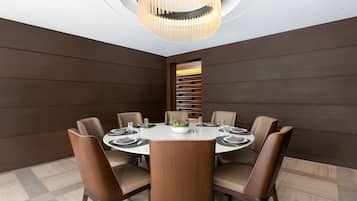 Un comedor moderno con una mesa redonda, seis sillas y una lámpara central.