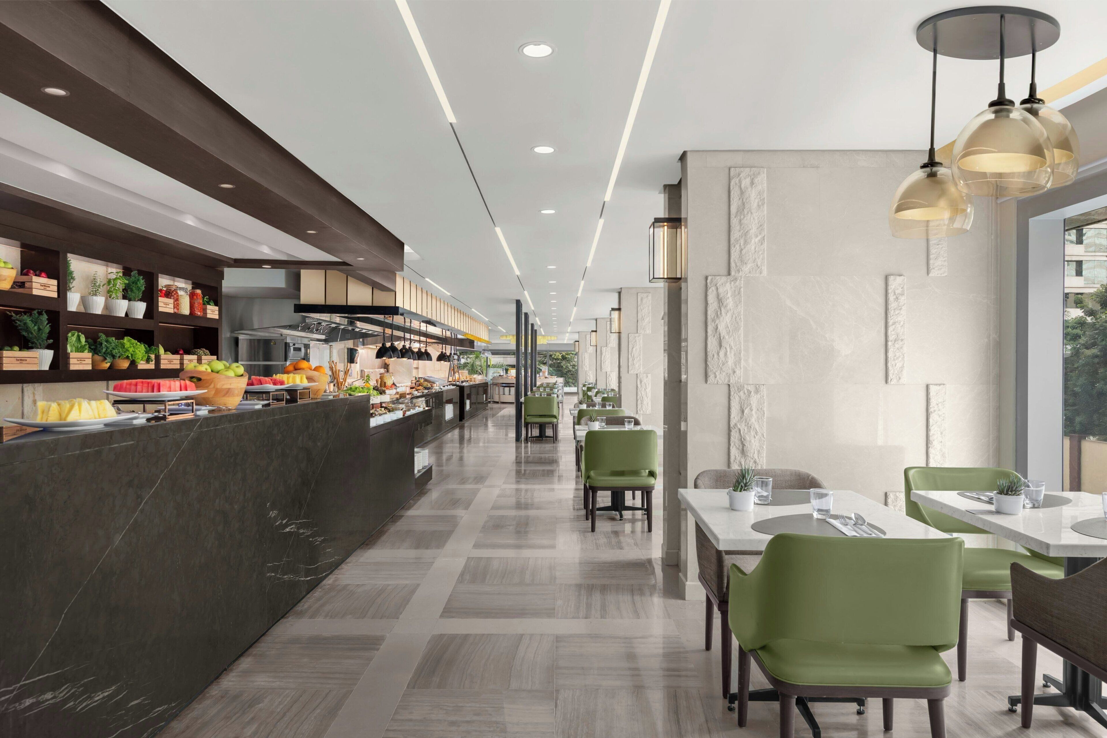 Un restaurant moderne avec un long comptoir, des chaises vertes et un sol en marbre.