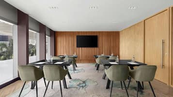 Une salle de conférence équipée d’un grand téléviseur à écran plat, de plusieurs tables et de chaises.