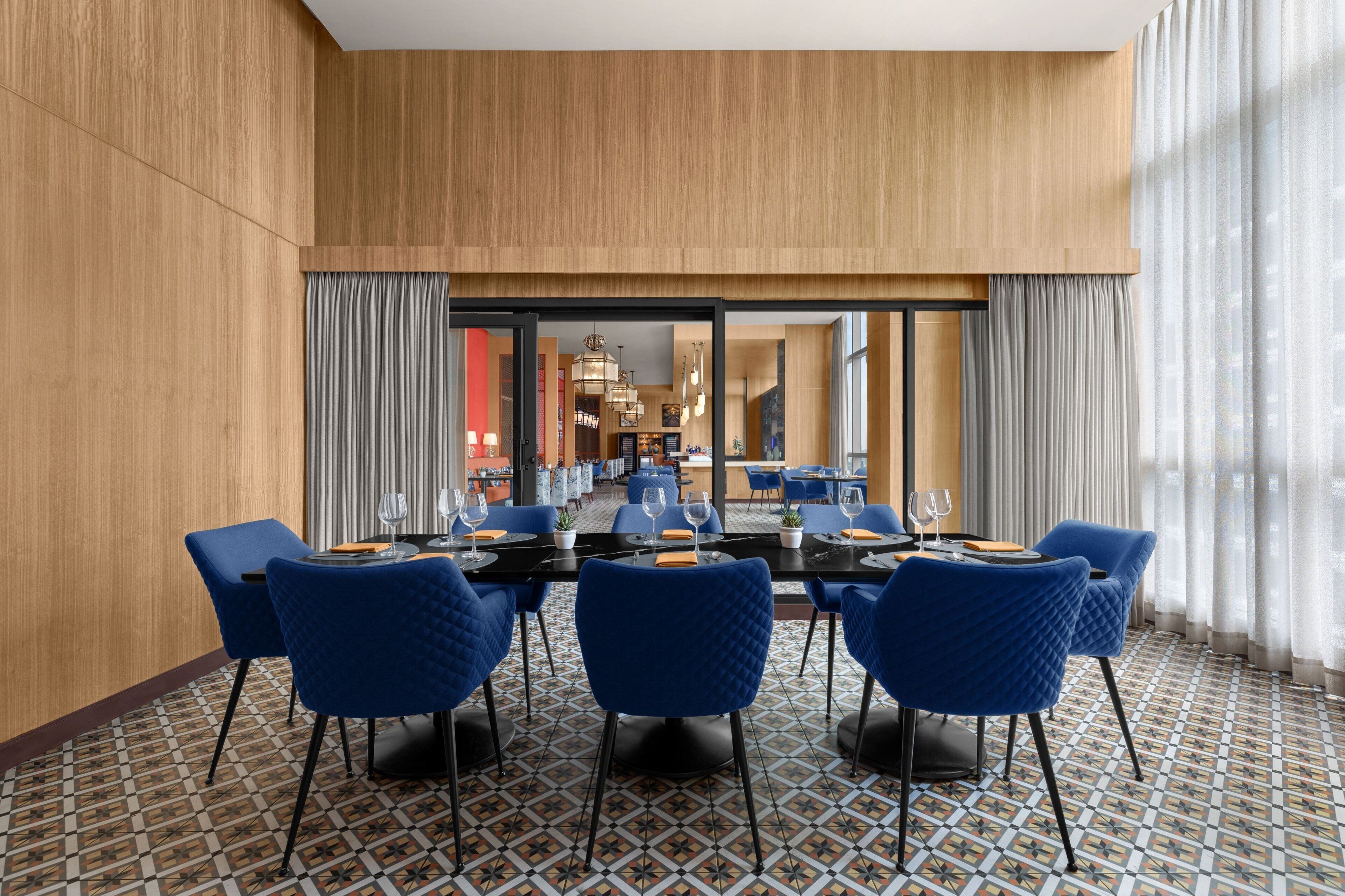Een eethoek met blauwe gestoffeerde stoelen, een patroon vloer en uitzicht op het restaurant.