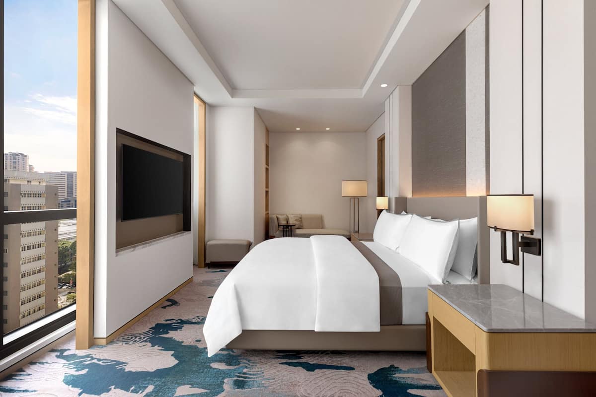 Une chambre d’hôtel moderne dotée d’un grand lit, d’un bureau, d’une télévision et offrant une vue sur la ville.