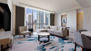 Une chambre d’hôtel moderne dotée d’une grande fenêtre, d’un canapé, d’une table basse et d’un téléviseur à écran plat.