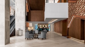 Un hall d’entrée spacieux avec un plafond haut, un escalier et un coin bar.