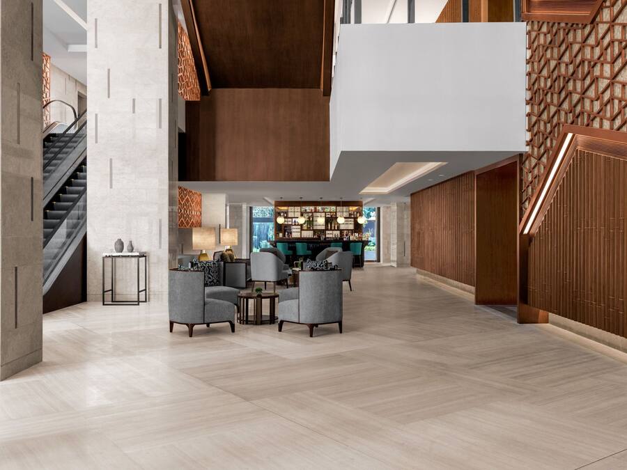 Un lobby amplio con techo alto, una escalera y una zona de bar.