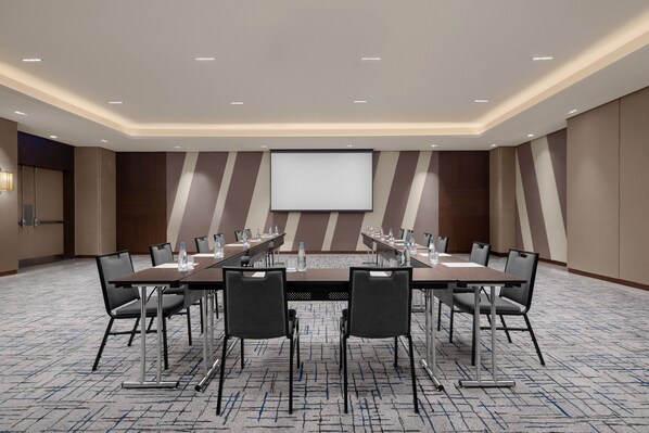 A conference room with a long table, multiple chairs, a projector screen, and a carpeted floor. - The Westin Manila (Mandaluyong)