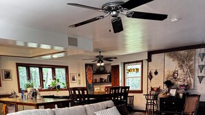 A modern living room with a sectional sofa, a dining area with a table and chairs, and a ceiling fan.