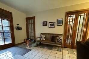 A living room with a wooden bench, a door, and a wall with three framed pictures.