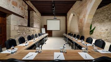 Een vergaderzaal met een lange tafel, stoelen en een projectiescherm.