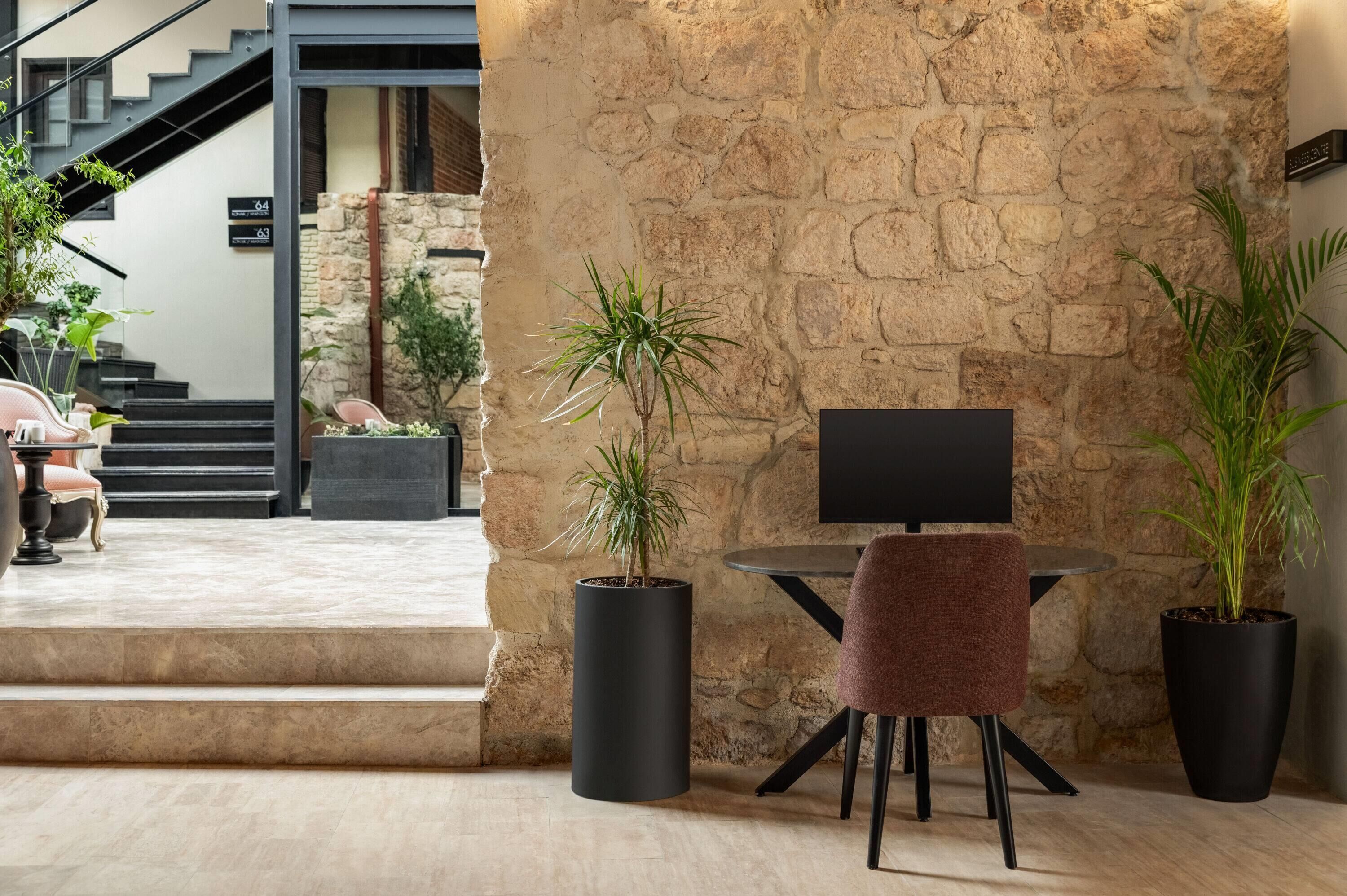 Un área de estar interior moderna con pared de piedra, un televisor de pantalla plana y plantas en macetas.