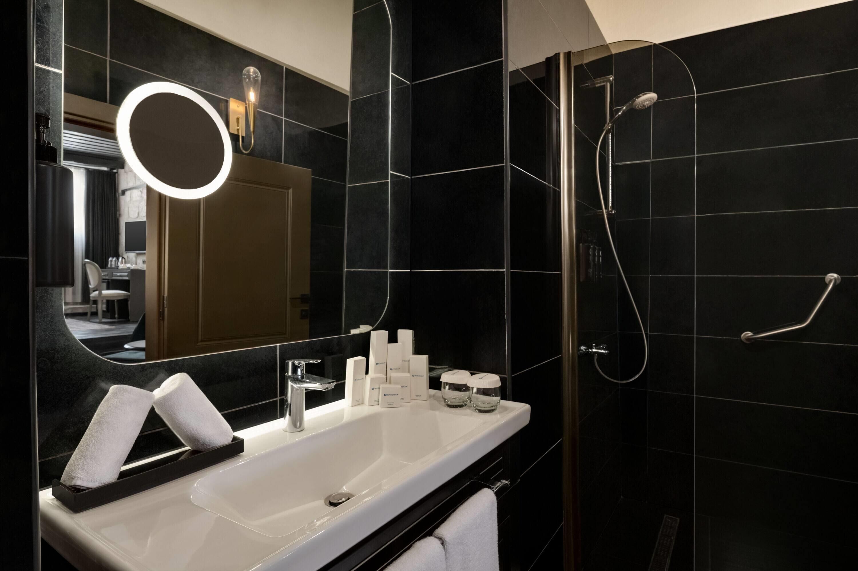 Une salle de bain moderne avec un grand miroir, un lavabo et une douche.