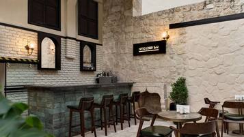 Una zona de bar con pared de piedra, sillas de madera y un letrero que dice 'NIYKS LOBBY BAR'.