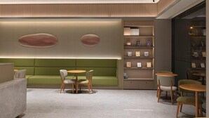 Een modern interieur met een groene bank, ronde tafels en boekenkasten.