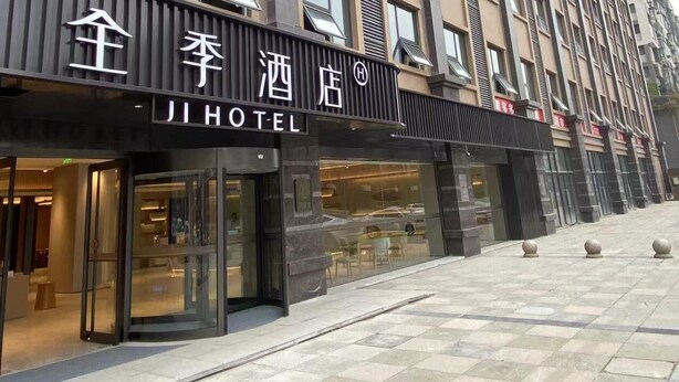 Een hotelgebouw met een moderne gevel, grote ramen en een opvallend bord met de naam Ji Hotel.
