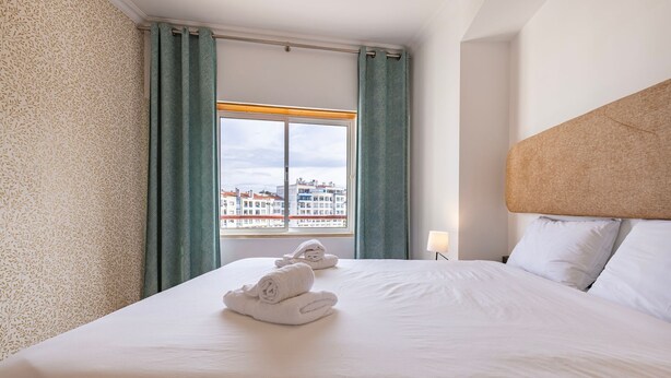 Una habitación de hotel con una cama grande, vistas de edificios a través de la ventana y un cabecero.
