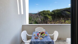Un balcón con una mesa dispuesta para una comida, con vista a un paisaje costero.