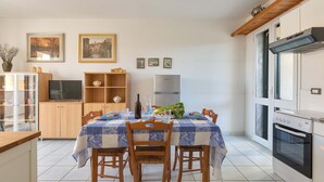 Una cocina moderna con una mesa de comedor para cuatro personas, horno empotrado y televisor sobre un mueble de madera.