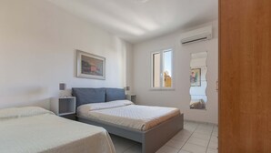 Un dormitorio con dos camas, una ventana y un equipo de aire acondicionado.