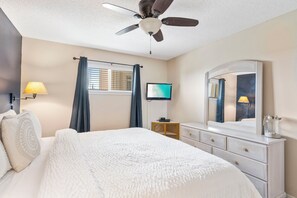A bedroom with a bed, a ceiling fan, a TV, a dresser, and a window with curtains. - Crystal Sands 309a - Gulf Front, Free Beach Service, Heated Pool, Sleeps 9 (Destin)