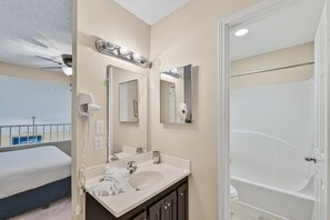 A hotel bathroom with a large mirror, a sink, and a bathtub. - Crystal Sands 309a - Gulf Front, Free Beach Service, Heated Pool, Sleeps 9 (Destin)