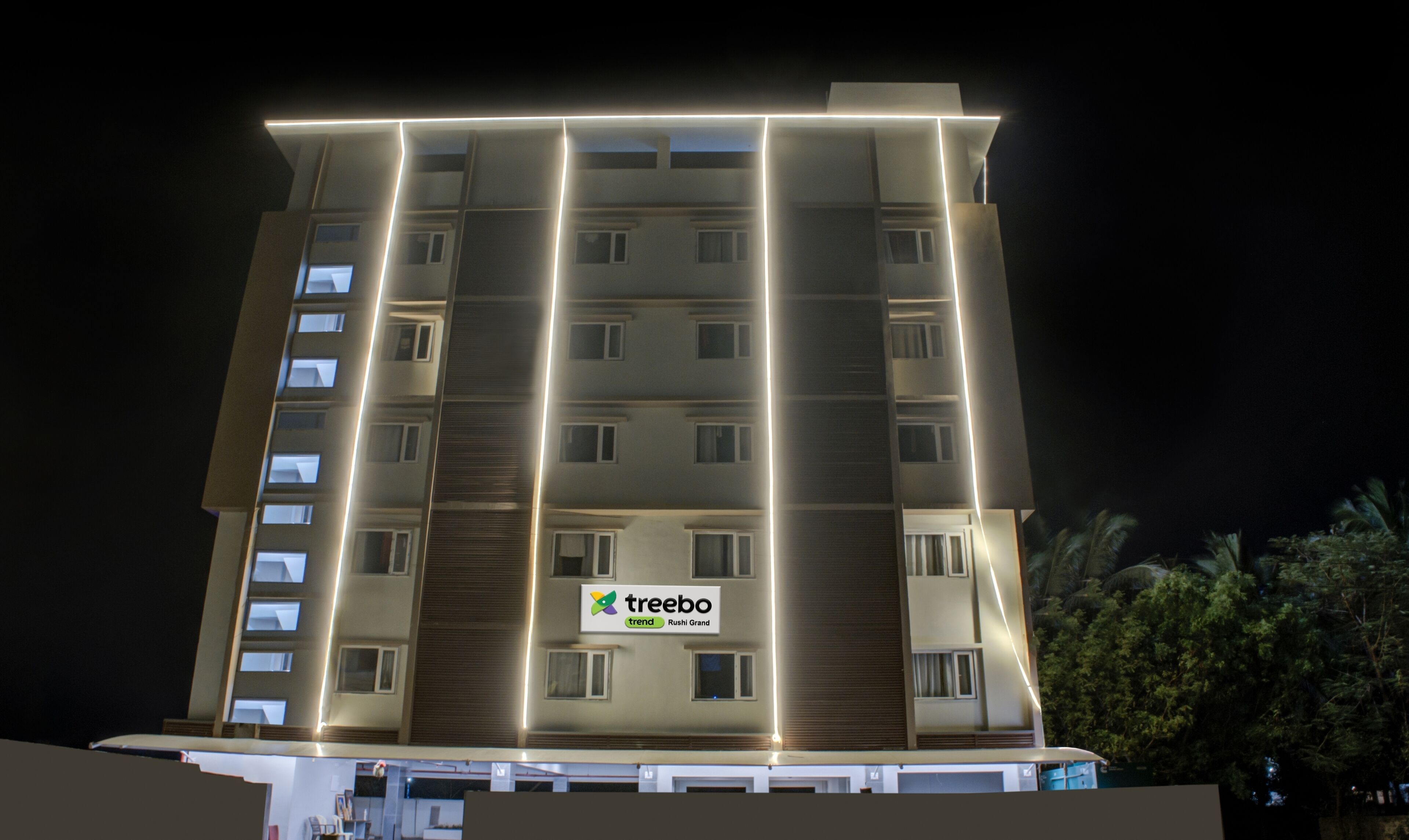 A multi-story hotel with a prominent 'treebo trend Rushi Grand' sign on the facade.