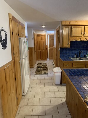 A kitchen with wooden cabinets, a tiled backsplash, and a refrigerator.