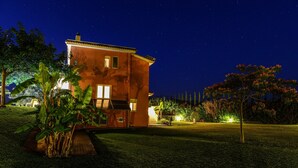 Una casa a due piani con un cortile anteriore ben illuminato di notte.