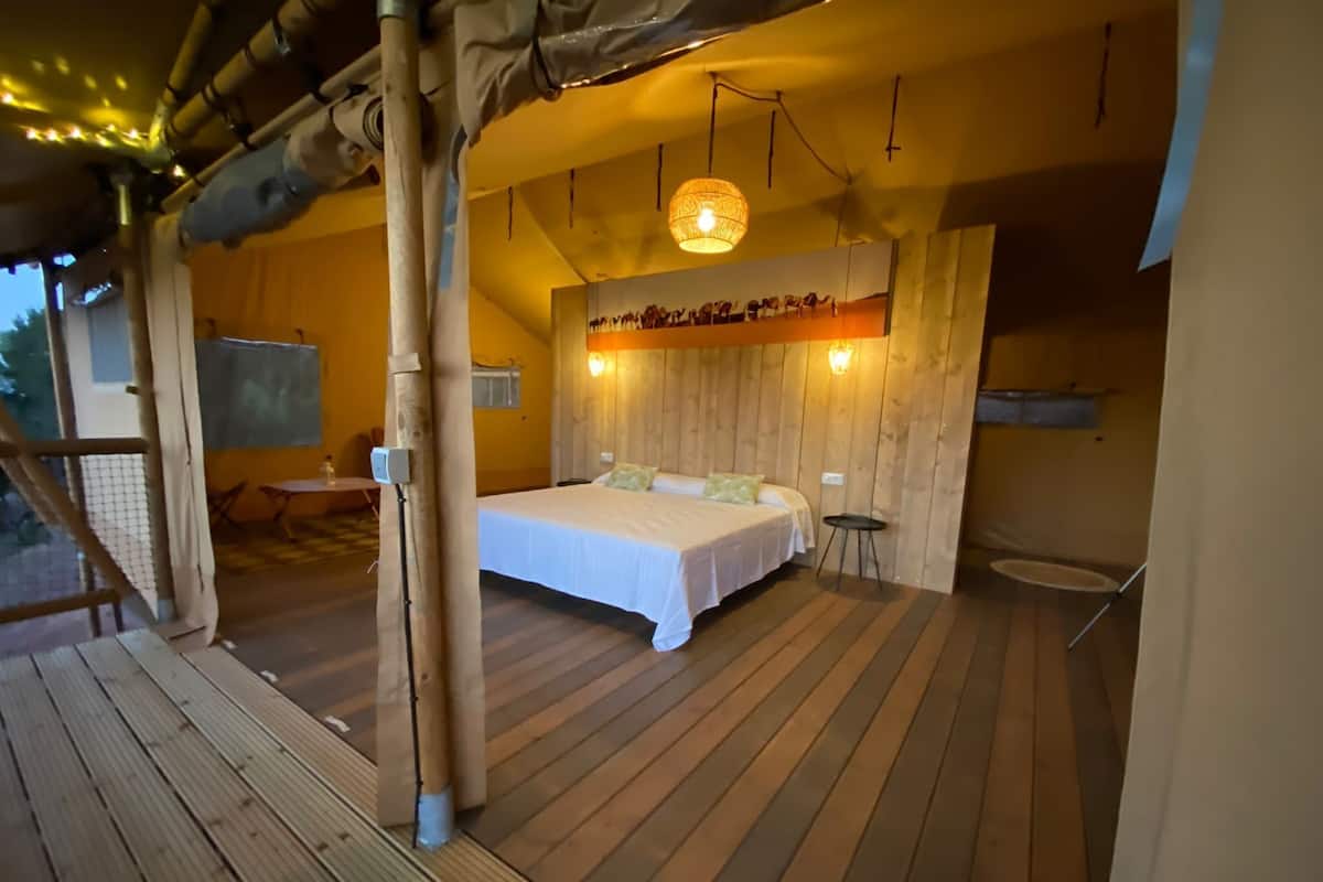 Un dormitorio con cama, una mesita pequeña y estante en la pared.