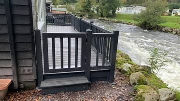A wooden deck with a railing overlooking a river.