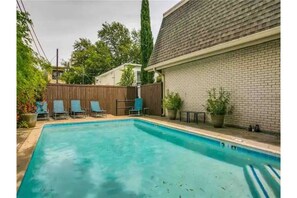 Relax by the rectangular pool surrounded by lounge chairs and a tree.