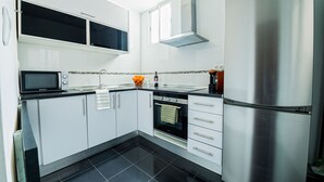 Een moderne keuken met witte kasten, een roestvrijstalen koelkast, een magnetron en een inbouwoven.