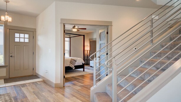 A modern interior with a staircase, wooden flooring, and a bedroom with a bed and nightstand.