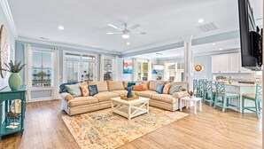 A spacious living room with a beige sectional sofa, a coffee table, and a patterned rug. - Luxe Home w/ Free Htd Pool, 50 Steps to Beach, Elevator, Putting Green, Tiki Bar (North Myrtle Beach)
