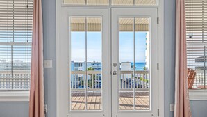A double door with glass panels, leading to a balcony with a view of the sea and buildings. - Luxe Home w/ Free Htd Pool, 50 Steps to Beach, Elevator, Putting Green, Tiki Bar (North Myrtle Beach)