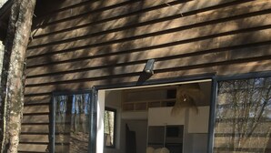 A wooden deck with a glass door leading to a modern interior with a kitchen and seating area. - Geres National Park barn (Arcos Valdevez)