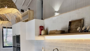 A modern kitchen with white cabinetry, a stainless steel refrigerator, a built-in oven, and a wooden countertop. - Geres National Park barn (Arcos Valdevez)