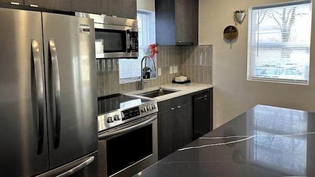 A modern kitchen with stainless steel appliances, a microwave, a sink, and a stove. - Modern Ranch near Knapp Center, Stadium, Downtown (Des Moines)