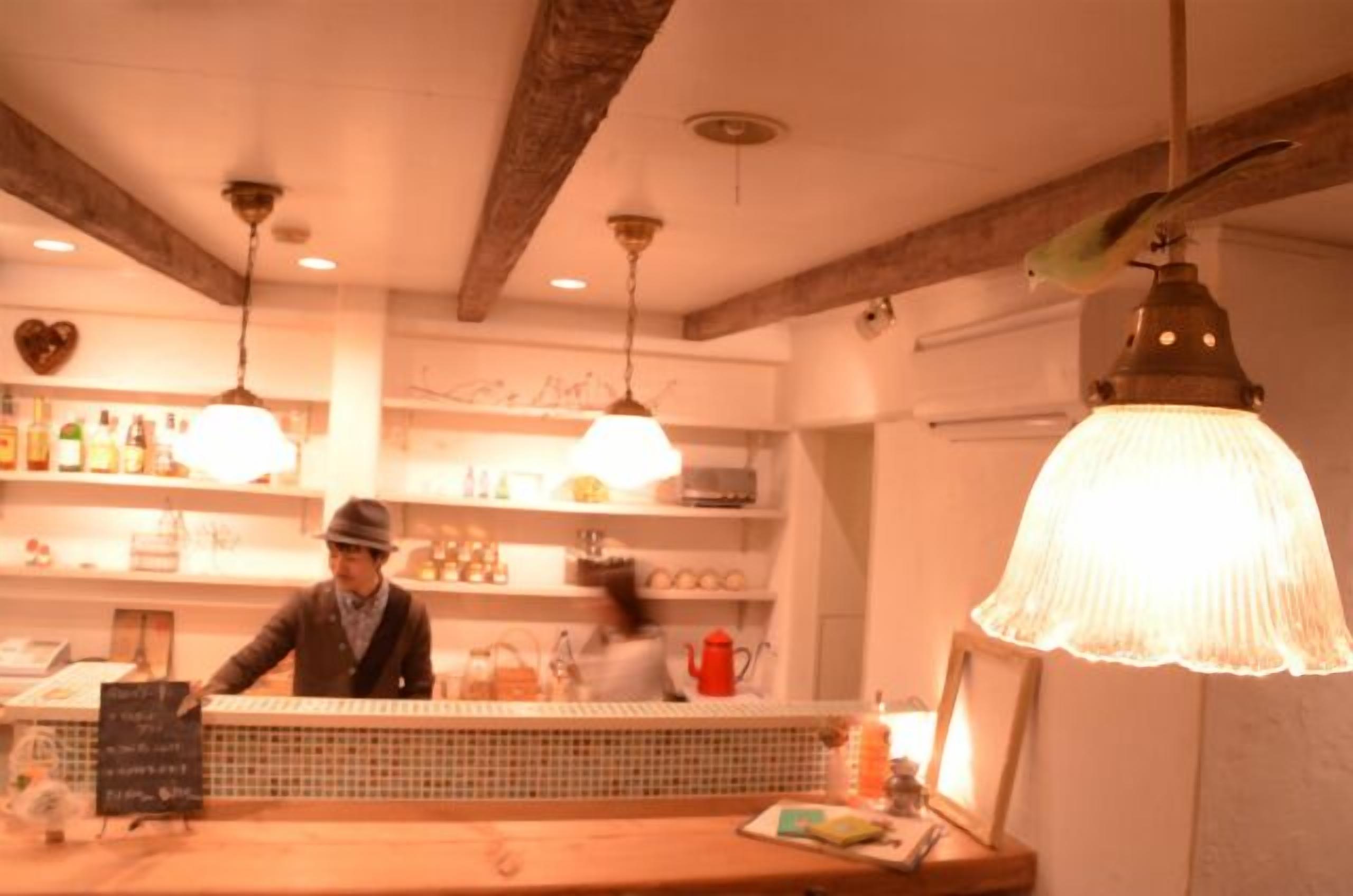 Un espace bar avec un comptoir, des étagères remplies de bouteilles et des luminaires suspendus.