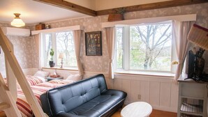 A cozy room with a black leather sofa, a small round table, and a bed with striped bedding.