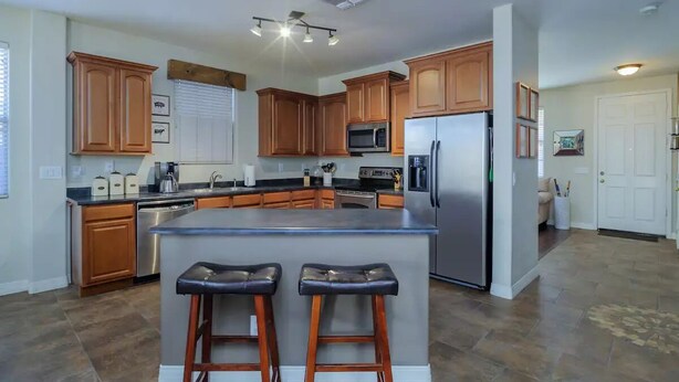 Una cocina moderna con armarios de madera, electrodomésticos de acero inoxidable y una isla central con taburetes de bar.