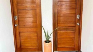 Two wooden doors with numbers 301 and 302, a potted plant, and a tiled floor. - Modern 302 apartment w/AC +WiFi + Parking (Cali)