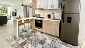 A modern kitchen with white cabinets, a stainless steel refrigerator, and a patterned floor. - Modern 302 apartment w/AC +WiFi + Parking (Cali)