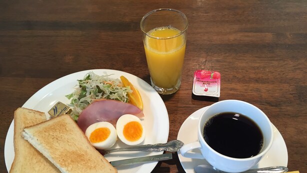 A plate with toast, ham, eggs, and a glass of orange juice. - Business Hotel B&B (Kato)