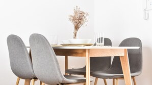 A dining table with four grey upholstered chairs, a white bowl, and a vase with dried flowers. - 7escalones Apartamentos Boutique (Rota)